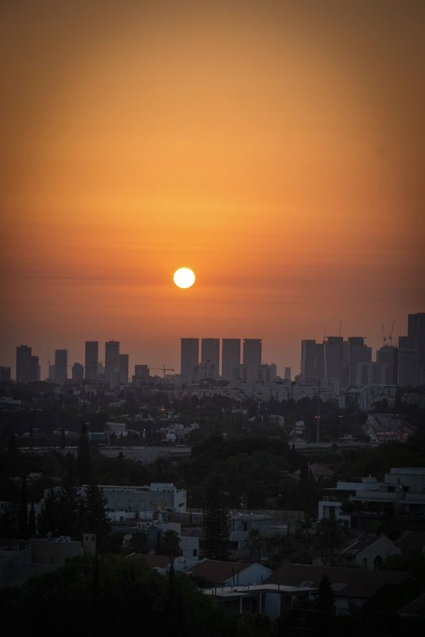 The sun setting in an orange sky over a distant skyline