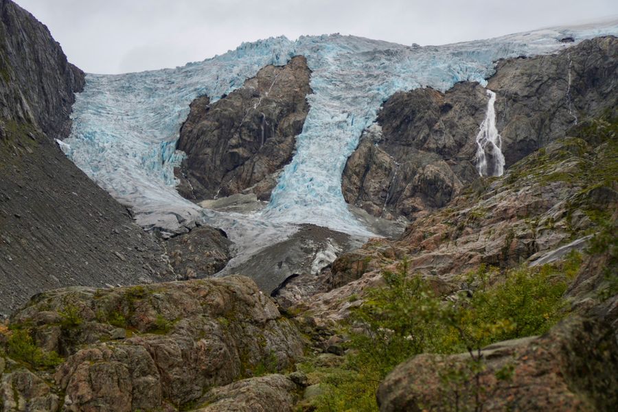 A glacier spilling between rocky slopes above a valley