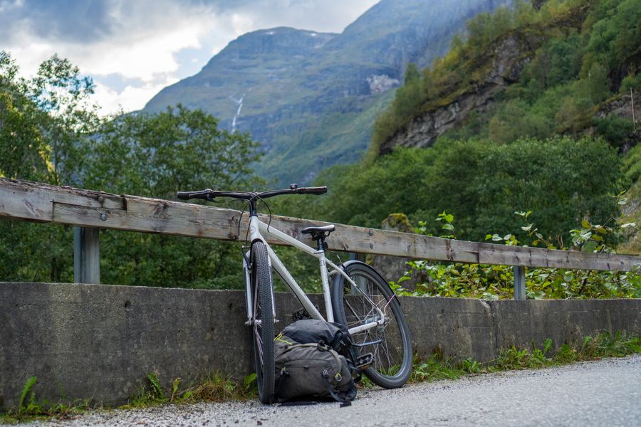 A bicycle leaning on a wooden railing above a mountain valley