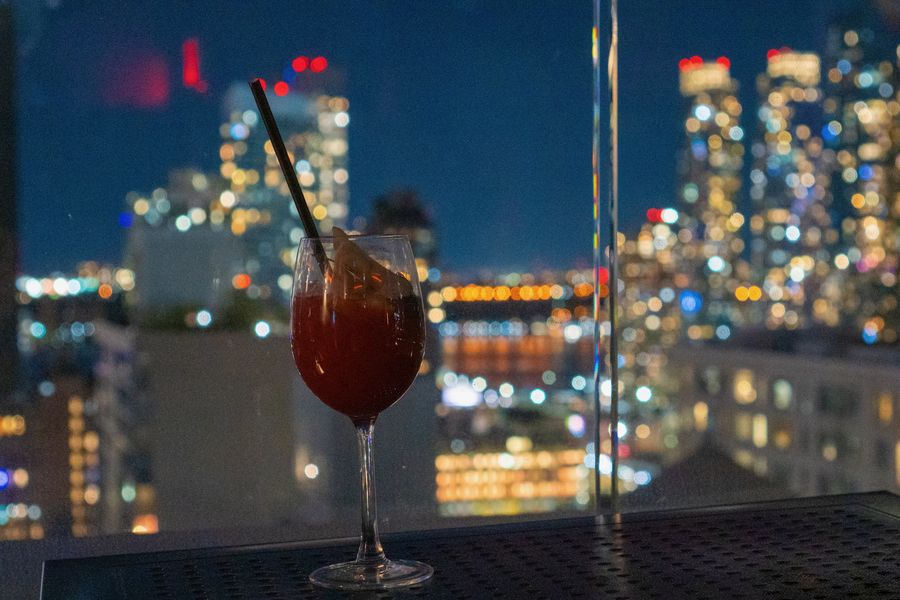 A red cocktail on a terrace with blurred city lights behind