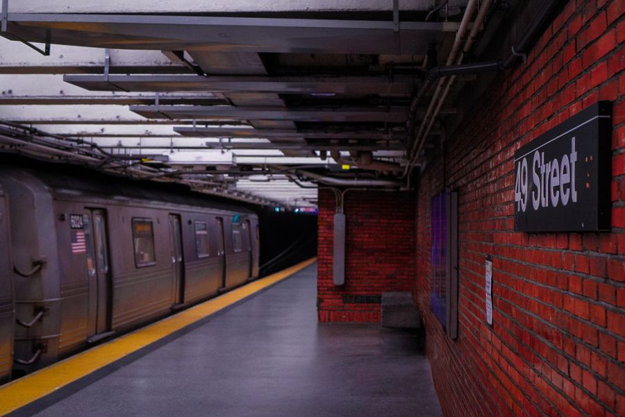 A subway train waiting at an empty platform beside a brick wall