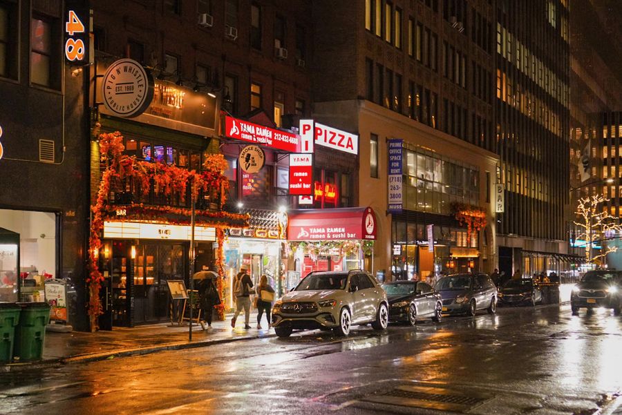 Neon storefronts reflecting on a wet street at night