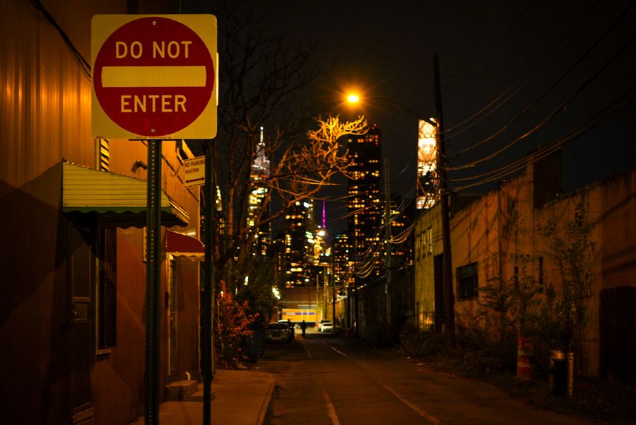 A Do Not Enter sign on a dark street with a lit tower behind