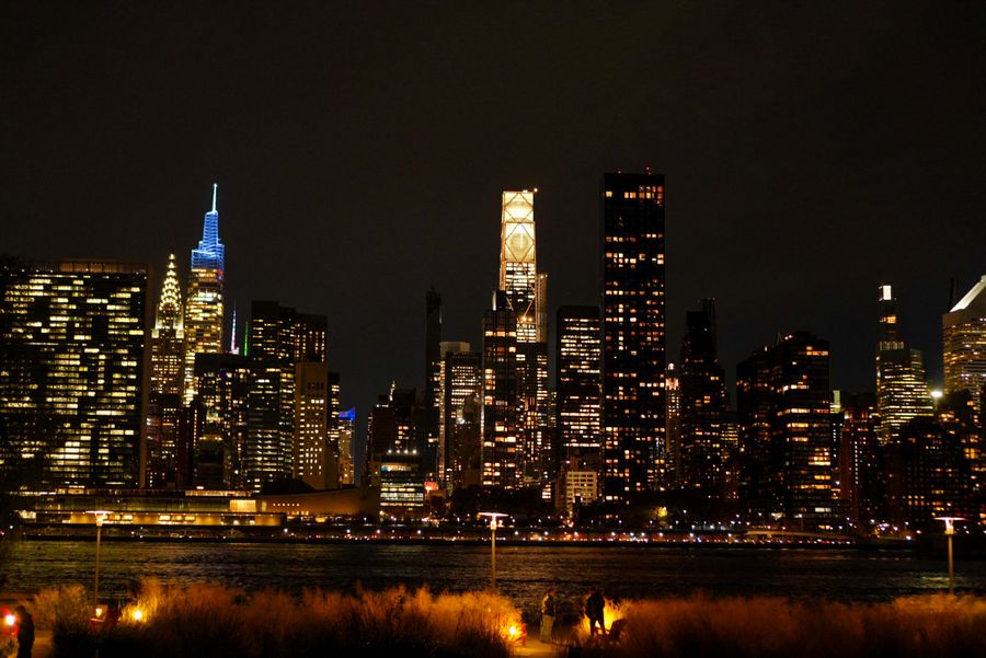 A city skyline lit up at night across dark water