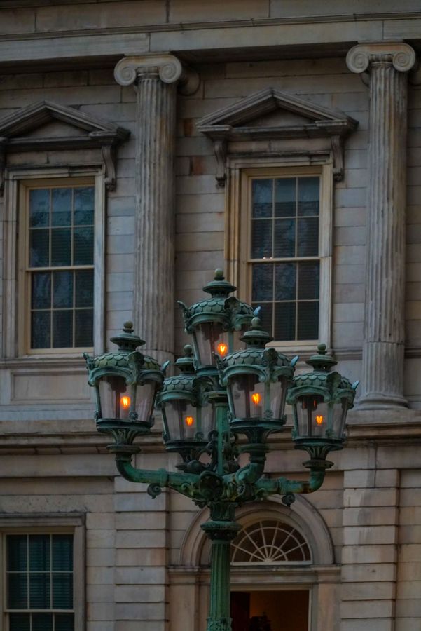 An ornate green street lamp in front of a classical facade