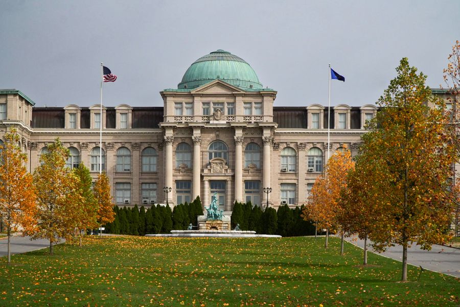 A grand domed building behind autumn trees and a lawn