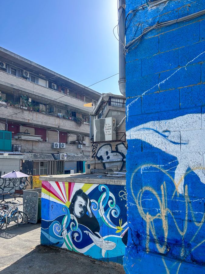 A street corner covered in blue murals and graffiti