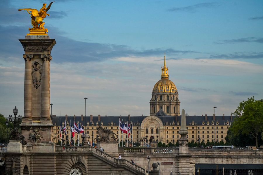 A gilded statue on a bridge pillar with a golden dome behind