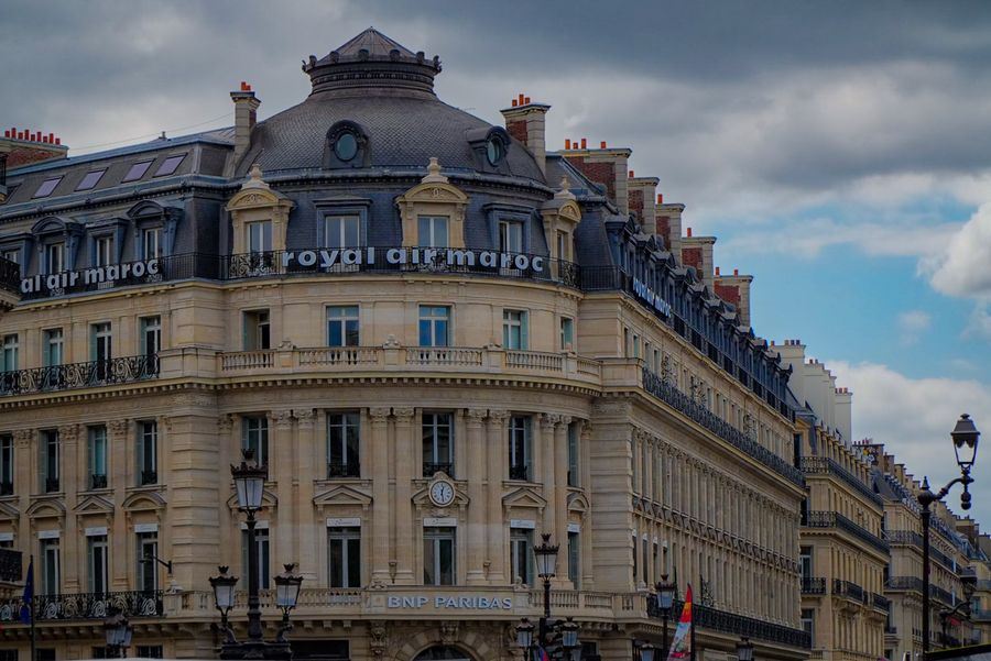 An ornate corner building in Paris under a cloudy sky