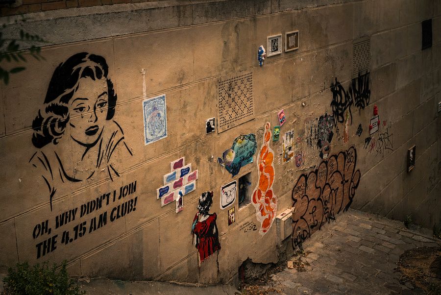 A pop-art stencil of a woman on a wall covered in street art