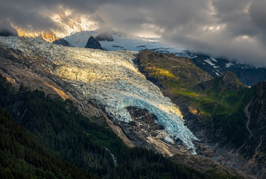 Evening light catching a glacier under dark clouds