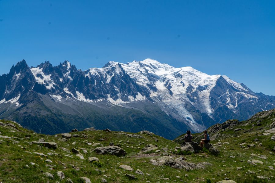 A snow-covered massif above green alpine slopes