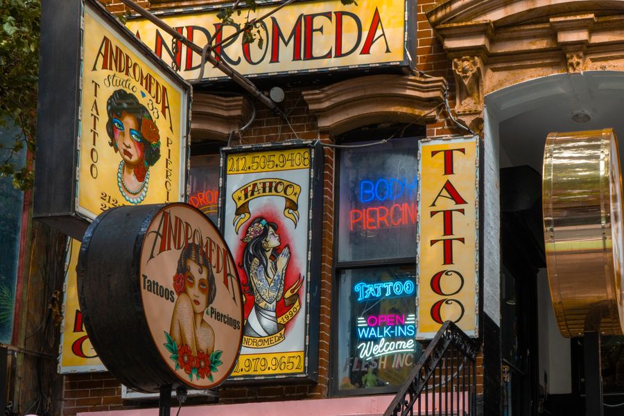 Old tattoo parlour signs crowded above a doorway