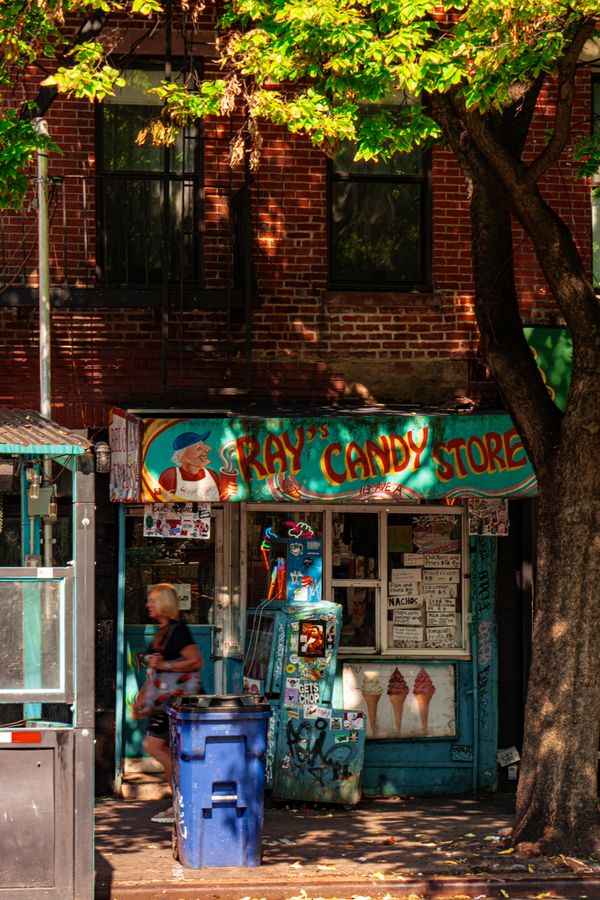 A small candy store front under a leafy tree