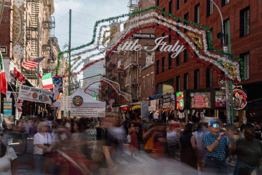 Crowds blurred under the Little Italy welcome arch