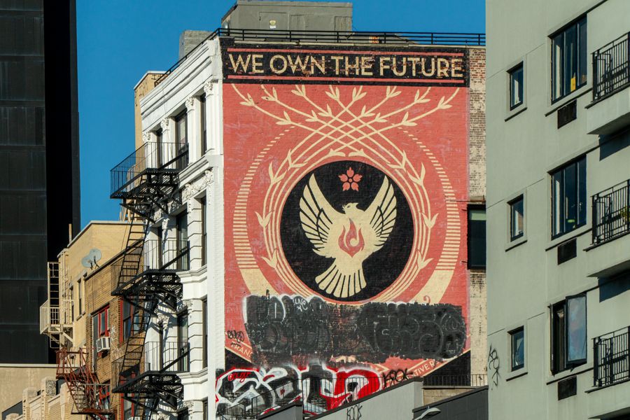 A large phoenix mural above a graffiti-covered wall