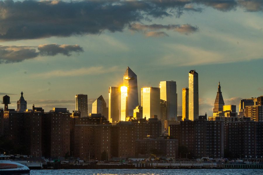 Sunset reflecting gold off a cluster of skyscrapers across the water