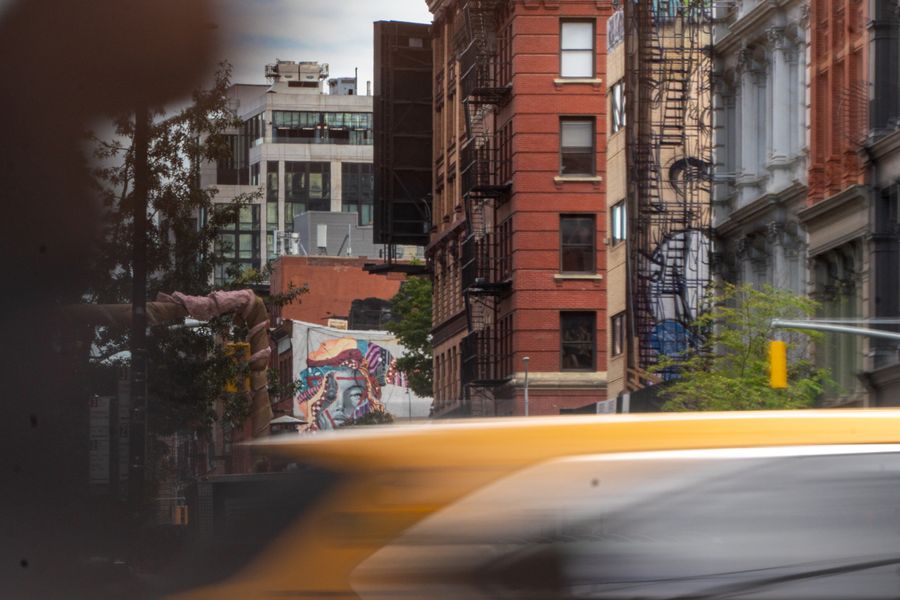 A yellow taxi blurring past old brick buildings