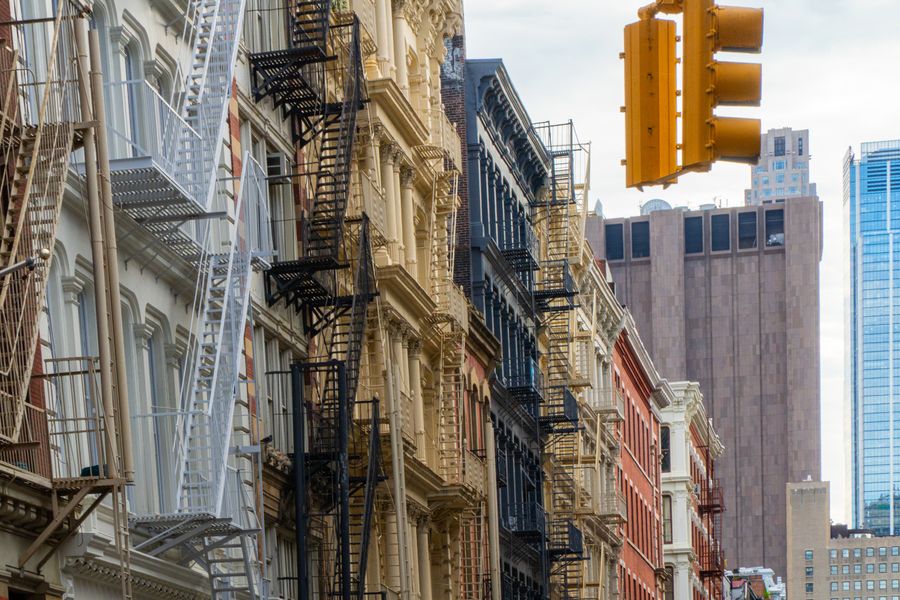 Fire escapes and a yellow traffic light on a cast-iron street