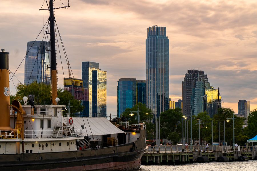An old tugboat in front of a city skyline at sunset