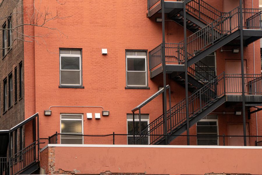 A red brick wall with black fire escapes in late light